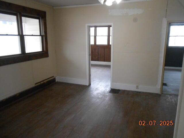 spare room featuring baseboards, wood finished floors, and crown molding