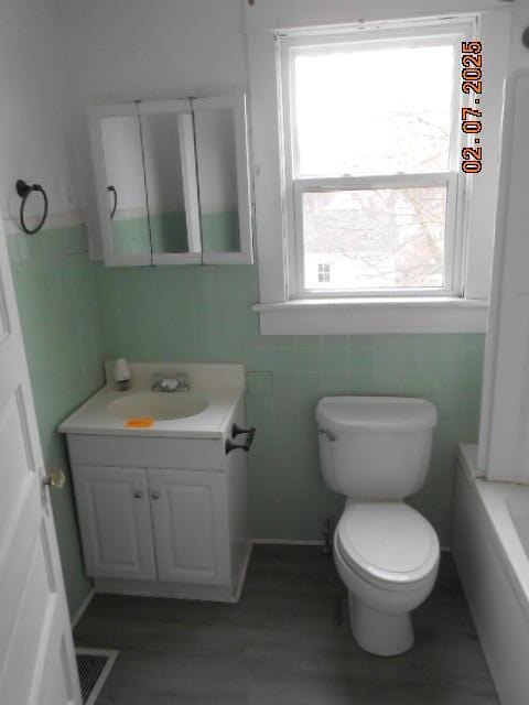 full bathroom featuring a healthy amount of sunlight, toilet, vanity, and wood finished floors