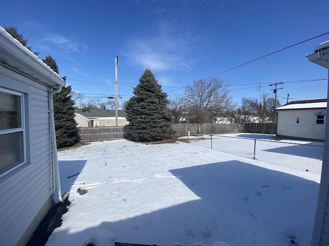 snowy yard featuring a fenced backyard