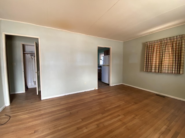 spare room featuring dark wood-style flooring, visible vents, and baseboards