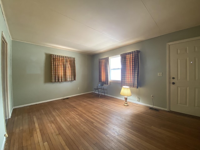 empty room with visible vents, baseboards, and wood finished floors