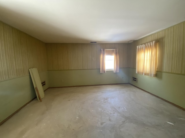 empty room with baseboards, visible vents, and unfinished concrete floors