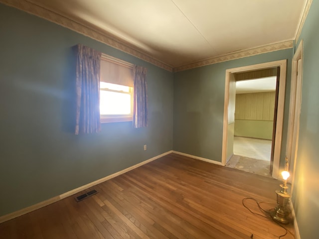 interior space with crown molding, wood finished floors, visible vents, and baseboards