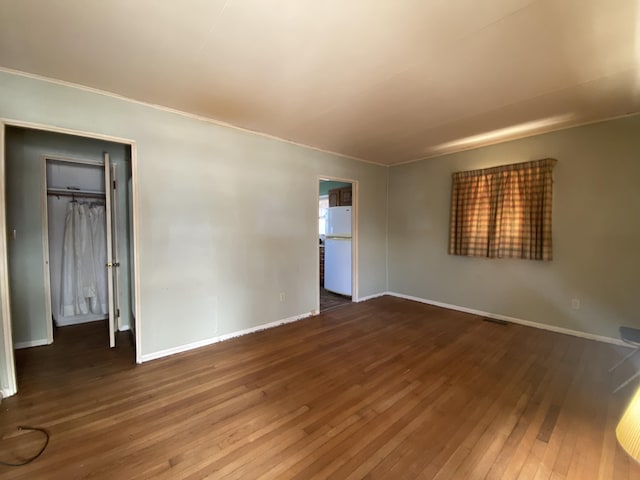 spare room featuring wood finished floors, visible vents, and baseboards