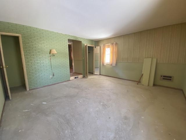 unfurnished bedroom featuring brick wall and concrete floors