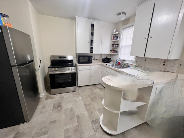 kitchen with stainless steel appliances, open shelves, light countertops, and white cabinets