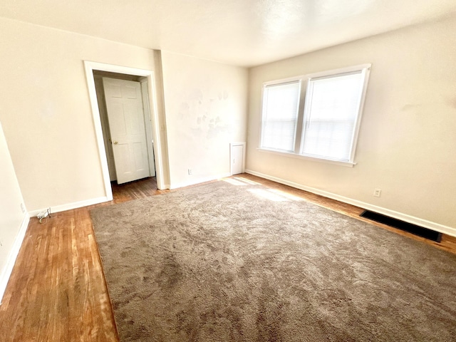 unfurnished bedroom featuring dark wood-style floors, visible vents, and baseboards