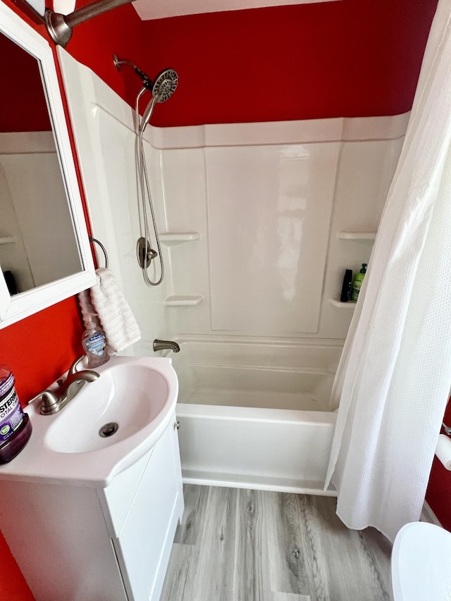 bathroom with shower / bath combo with shower curtain, a sink, and wood finished floors