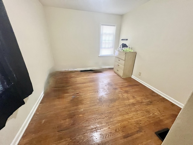 unfurnished room featuring dark wood-type flooring and baseboards