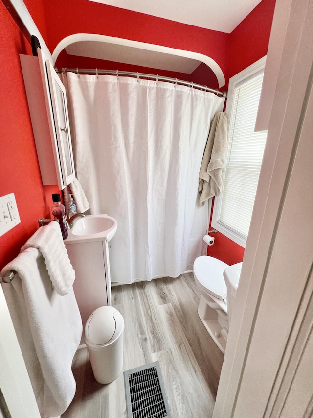 full bath with visible vents, vanity, toilet, and wood finished floors