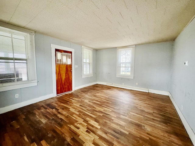 spare room with a baseboard radiator, baseboards, and wood finished floors