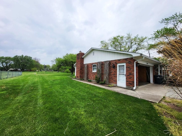 2169 State Route 49, Arcanum, OH 45304 - view of side of property with a lawn, a chimney, brick siding, concrete driveway, and an attached garage