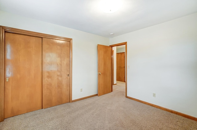 unfurnished bedroom with light carpet and a closet