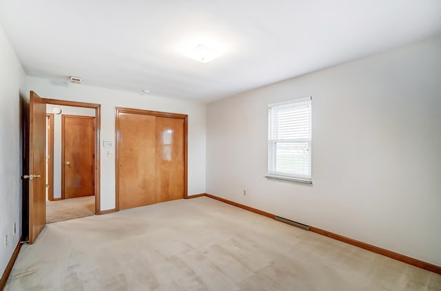 unfurnished bedroom with light carpet and a closet