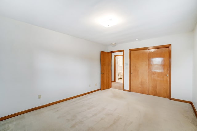 unfurnished bedroom with light colored carpet and a closet