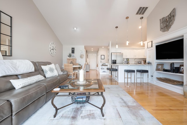 living room with high vaulted ceiling and light hardwood / wood-style flooring