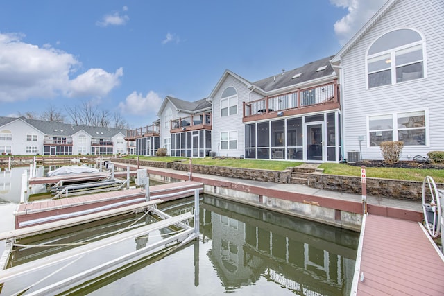 view of dock with central AC unit, a lawn, and a water view