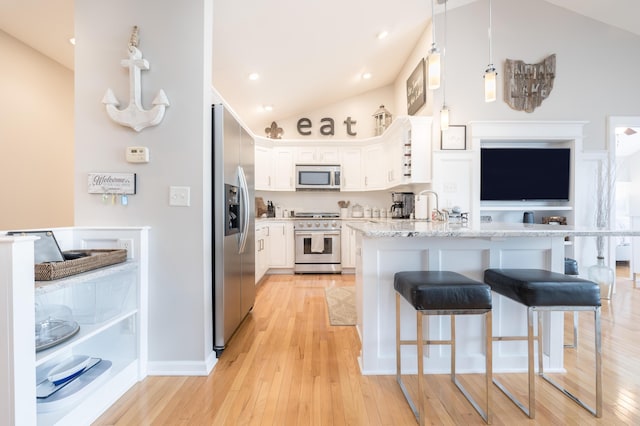 kitchen with light hardwood / wood-style flooring, hanging light fixtures, appliances with stainless steel finishes, light stone countertops, and white cabinets