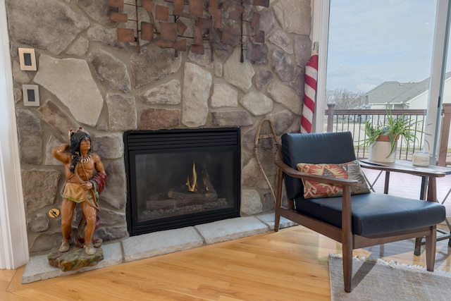 living area with wood-type flooring and a stone fireplace