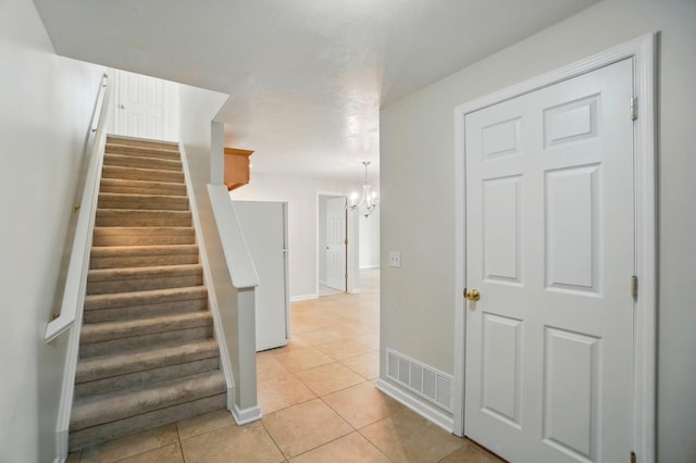 stairs with visible vents, baseboards, tile patterned floors, and a chandelier