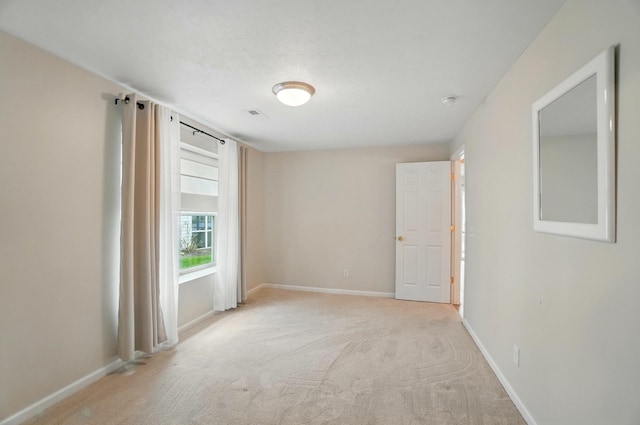 empty room with baseboards, light colored carpet, and visible vents
