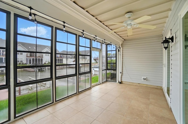 unfurnished sunroom featuring a water view and a ceiling fan