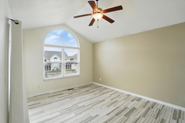 empty room featuring a ceiling fan, baseboards, light wood finished floors, and lofted ceiling