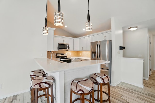 kitchen with decorative backsplash, appliances with stainless steel finishes, a peninsula, and a kitchen breakfast bar