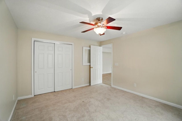 unfurnished bedroom featuring a closet, a ceiling fan, baseboards, and light carpet