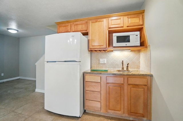 kitchen with decorative backsplash, a sink, light stone counters, light tile patterned floors, and white appliances
