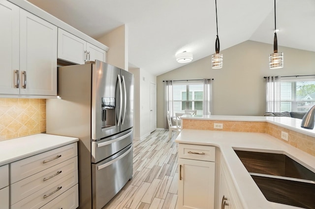 kitchen featuring vaulted ceiling, stainless steel fridge, a sink, and a healthy amount of sunlight