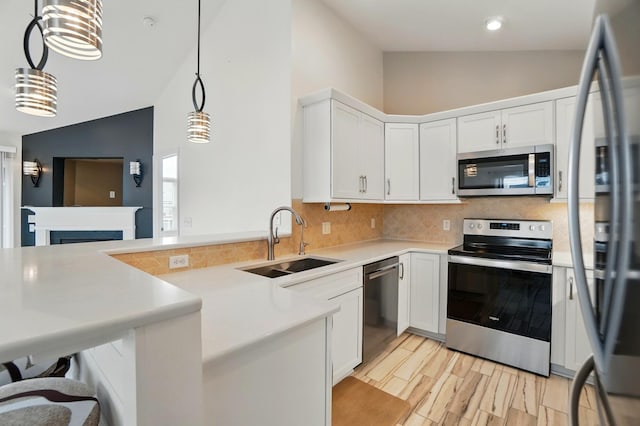 kitchen with backsplash, a sink, light countertops, a peninsula, and stainless steel appliances