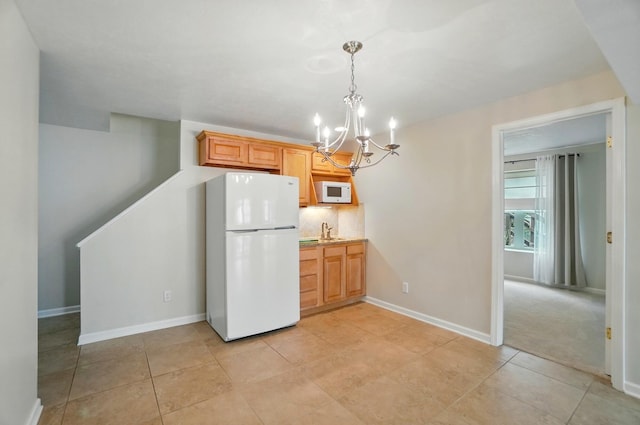 kitchen with an inviting chandelier, white appliances, baseboards, a sink, and decorative light fixtures
