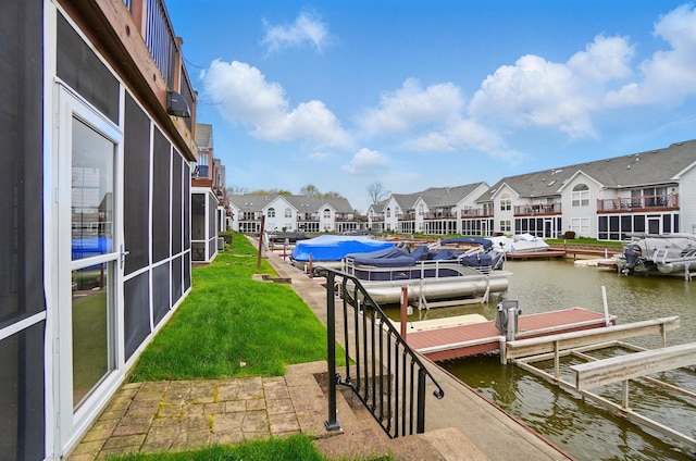 dock area featuring a residential view, boat lift, a water view, and a lawn