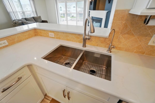 interior details featuring a sink, a multi sided fireplace, backsplash, and light countertops