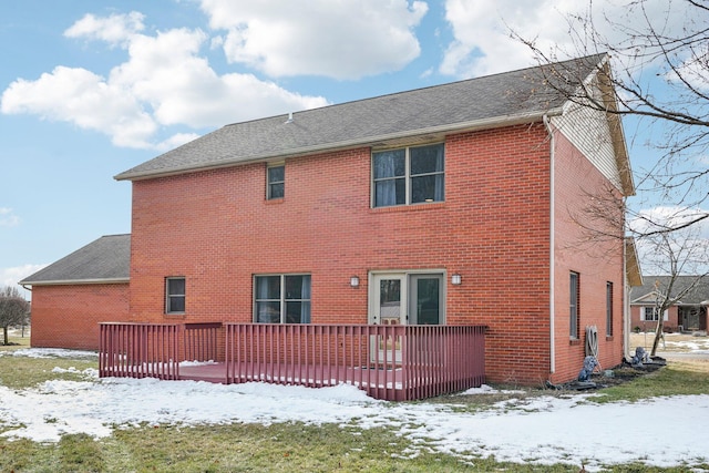 snow covered rear of property with a deck