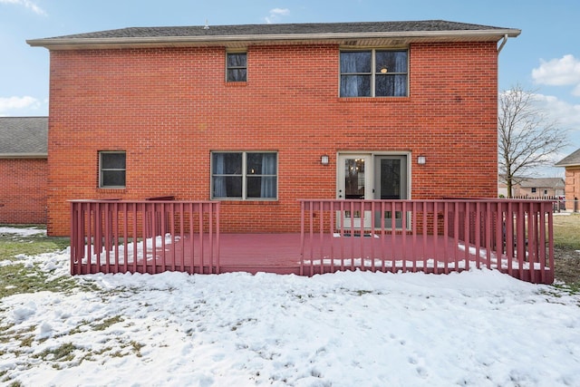 snow covered rear of property with a deck