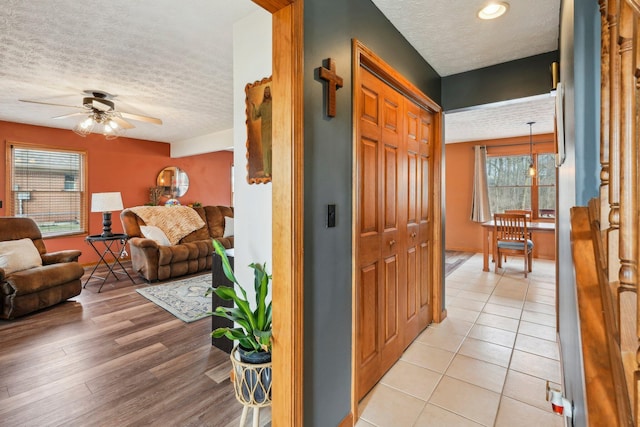 hall featuring light tile patterned floors and a textured ceiling