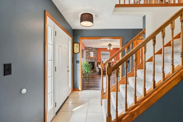 tiled foyer entrance with a brick fireplace and a textured ceiling