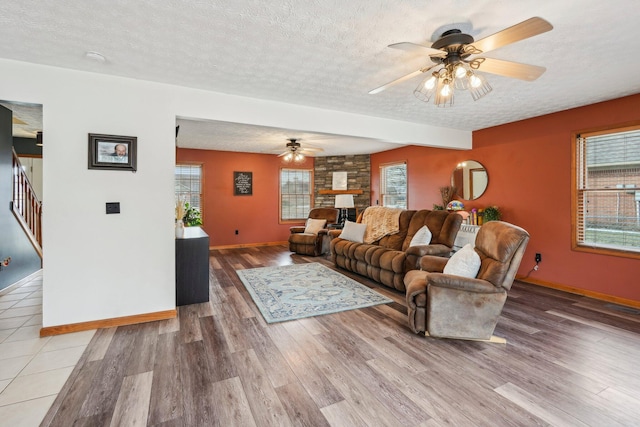 living room featuring ceiling fan, wood-type flooring, a fireplace, and a textured ceiling