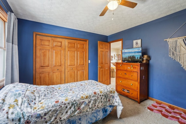 carpeted bedroom with ceiling fan, a closet, and a textured ceiling