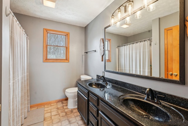 bathroom with vanity, toilet, and a textured ceiling