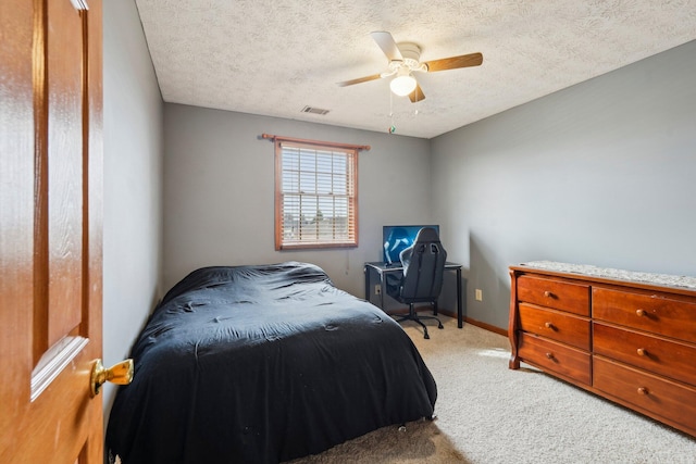 bedroom with ceiling fan, light carpet, and a textured ceiling