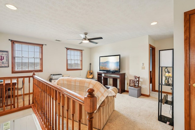 living room featuring ceiling fan, light carpet, and a textured ceiling