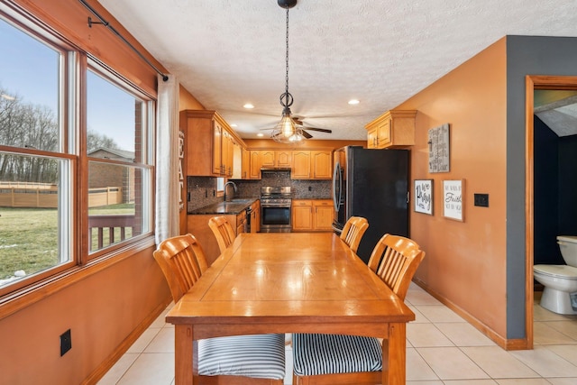 tiled dining space featuring a healthy amount of sunlight, sink, and a textured ceiling