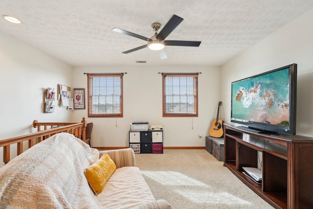 carpeted living room featuring ceiling fan, plenty of natural light, and a textured ceiling