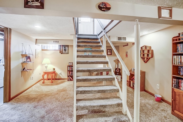 stairway with a textured ceiling and carpet