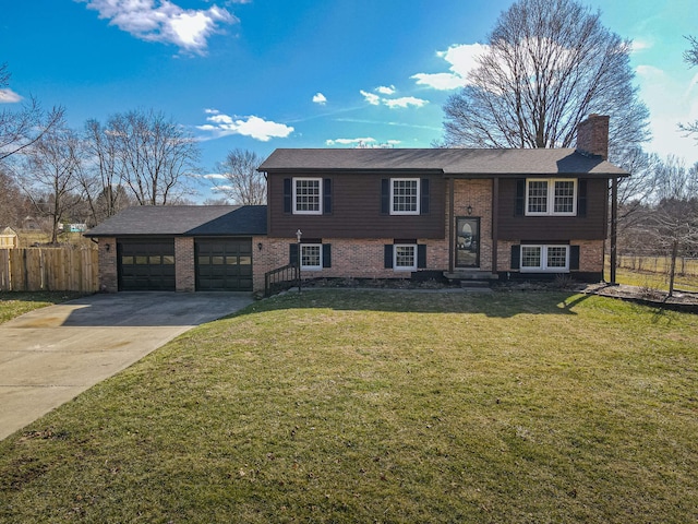 bi-level home featuring driveway, a chimney, an attached garage, fence, and a front yard