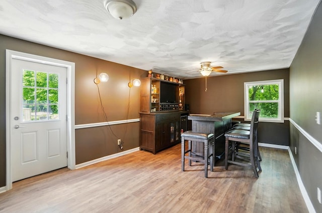 1370 Carpenter Rd, Bellbrook, OH 45305 - dining room featuring a bar, ceiling fan, baseboards, light wood finished floors, and a textured ceiling