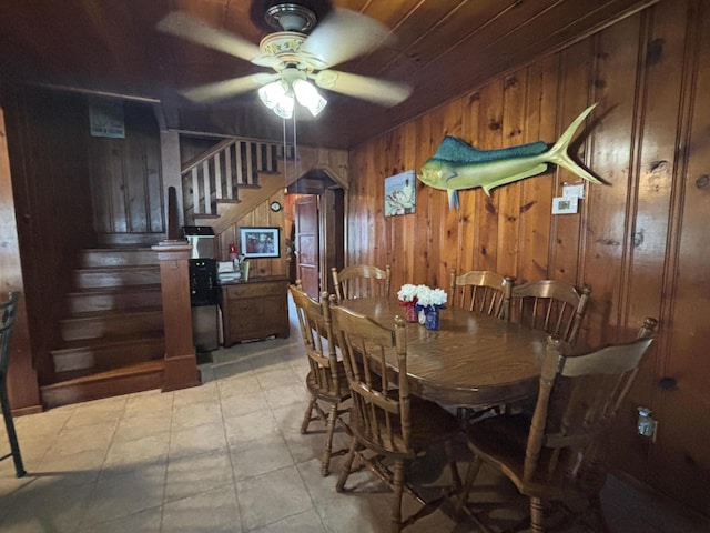 9029 Maple St, Huntsville, OH 43324 - dining space featuring stairway, a ceiling fan, and wood walls